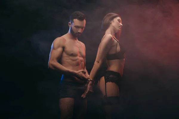 Красива еротична пара з наручниками в димчастій кімнаті — стокове фото