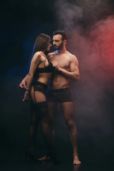 Beautiful passionate couple with handcuffs in smoky room — Stock Photo