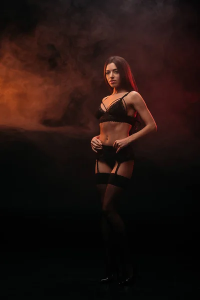 Jeune femme sexuelle posant en dentelle lingerie dans la chambre fumée — Photo de stock