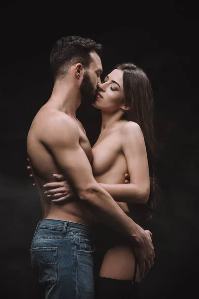 Novio apasionado abrazar y besar novia desnuda, aislado en negro - foto de stock