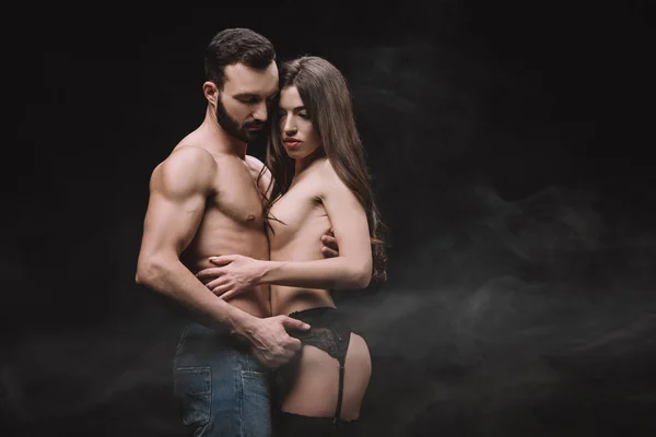 Sexual boyfriend hugging nude girlfriend, isolated on black with smoke — Stock Photo