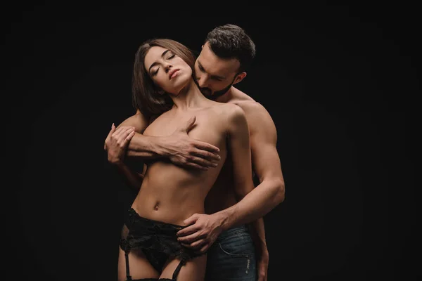 Bello fidanzato abbracciare nudo seno di bella fidanzata, isolato su nero — Foto stock