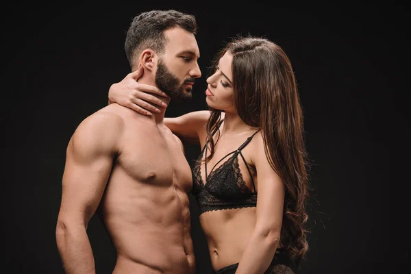 Bela mulher abraçando sexy shirtless homem isolado no preto — Fotografia de Stock