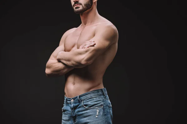 Visão cortada do homem muscular posando com os braços cruzados isolados no preto — Fotografia de Stock