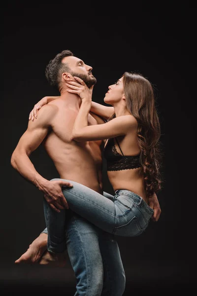 Heterosexual pareja apasionada abrazo aislado en negro - foto de stock