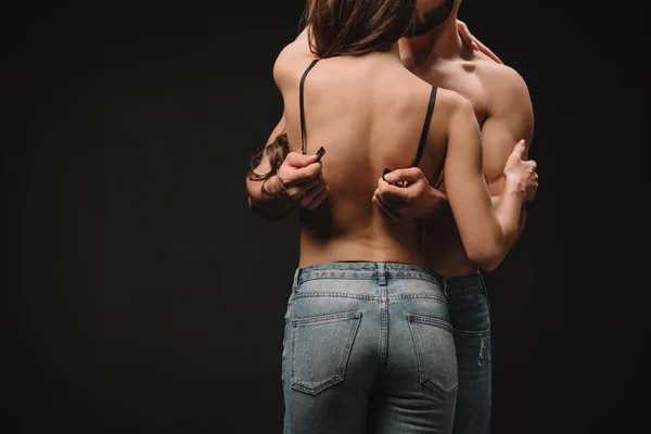 Cropped view of man undressing erotic woman isolated on black — Stock Photo