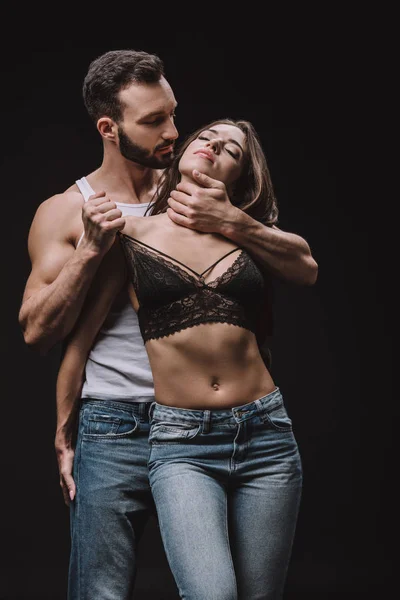 Passionate man hugging girl in lace bra isolated on black — Stock Photo