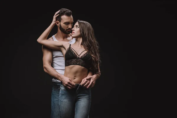 Sexy homem abraçando menina no sutiã de renda isolado no preto — Fotografia de Stock