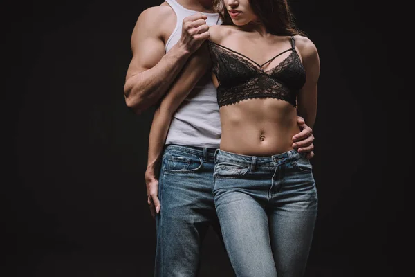 Cropped view of man undressing girl in lace bra isolated on black — Stock Photo