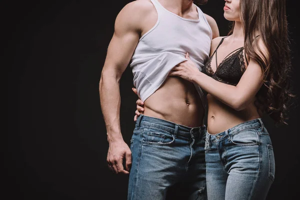Cropped view of woman undressing man in singlet isolated on black — Stock Photo