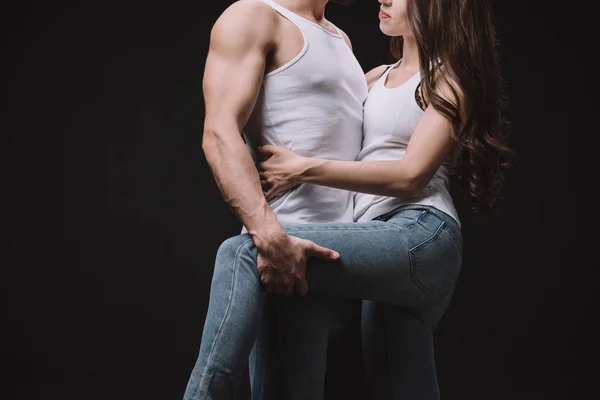 Recortado vista de hombre abrazando chica en blanco singlet aislado en negro - foto de stock