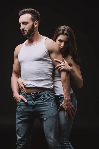 Beautiful woman hugging boyfriend in white singlet isolated on black — Stock Photo