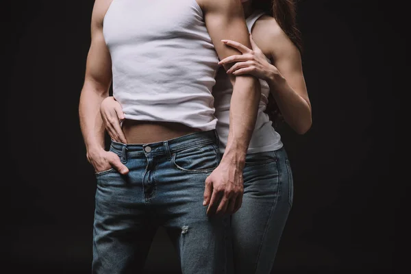 Corte vista de mulher abraçando namorado no branco singlet isolado no preto — Fotografia de Stock