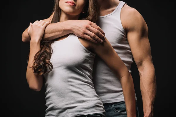 Обрізаний вид чоловіка, що обіймає дівчину в білому синглі ізольовано на чорному — стокове фото