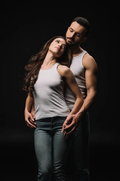 Homem abraçando mulher atraente no branco singlet isolado no preto — Fotografia de Stock