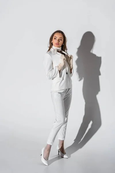 Привлекательная девушка в костюме позирует на белом фоне — стоковое фото