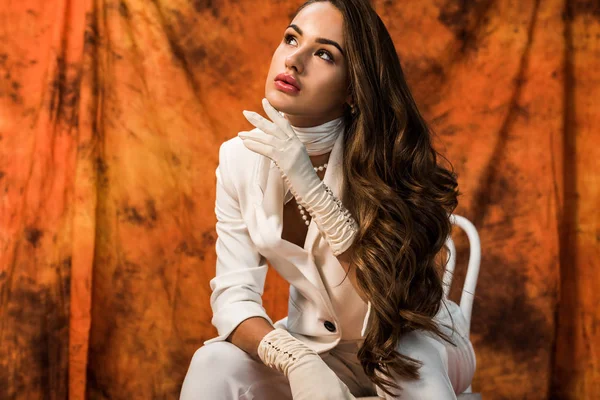 Hermosa chica en traje blanco sentado en silla sobre fondo texturizado - foto de stock