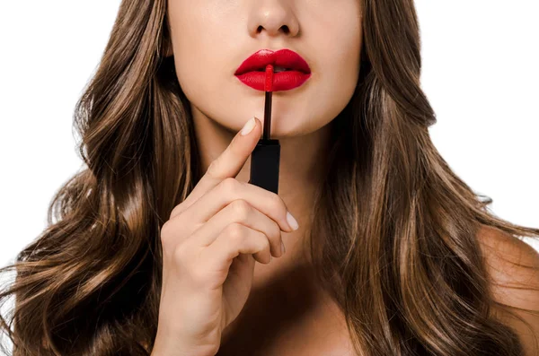 Vista recortada de chica con el pelo largo aplicando lápiz labial líquido rojo aislado en blanco - foto de stock