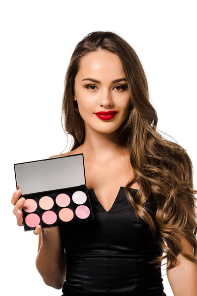 Beautiful girl in black dress with red lips holding palette with eyeshadows, looking at camera and smiling isolated on white — Stock Photo