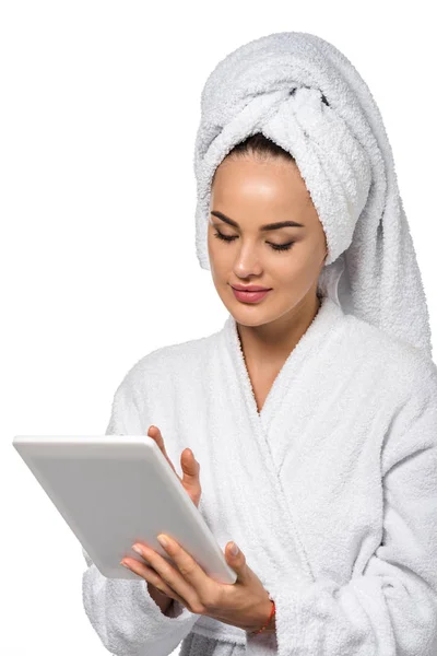 Beautiful girl in bathrobe using digital tablet isolated on white — Stock Photo