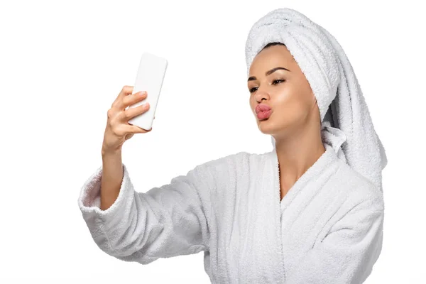 Hermosa chica en albornoz tomando selfie aislado en blanco - foto de stock