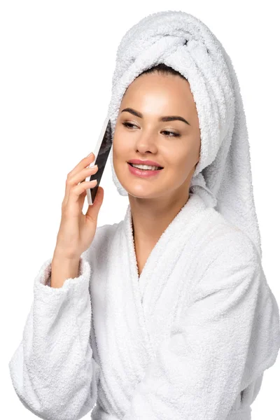 Chica atractiva en albornoz hablando en el teléfono inteligente aislado en blanco - foto de stock