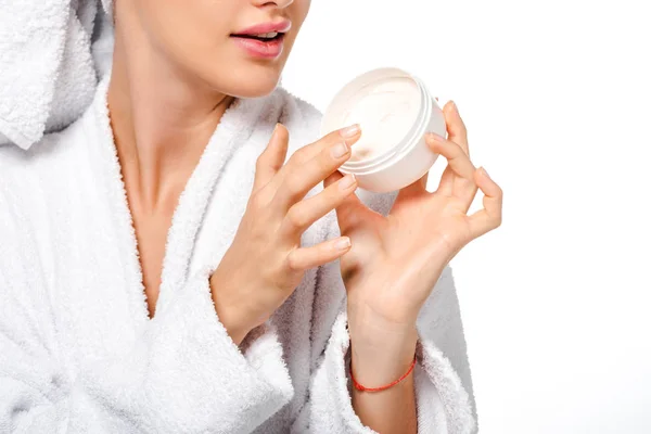 Cropped view of girl in bathrobe holding jar with cream isolated on white — Stock Photo