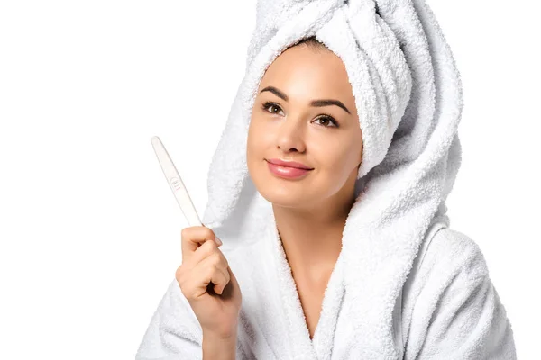 Dreamy girl in bathrobe holding pregnancy test isolated on white — Stock Photo