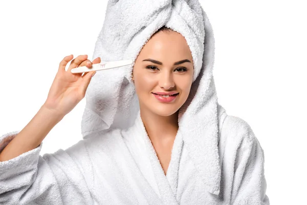 Schöne Mädchen im Bademantel zeigt Schwangerschaftstest, blickt in die Kamera und lächelt isoliert auf weiß — Stockfoto