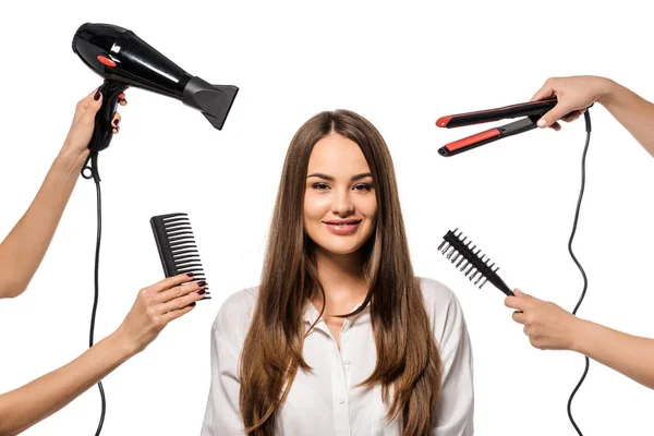 Mujeres sosteniendo accesorios de peluquería alrededor de hermosa chica mirando a la cámara - foto de stock