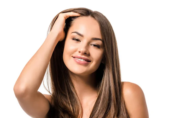 Bella donna sorridente, toccando lunghi capelli castani e guardando la fotocamera isolata sul bianco — Foto stock