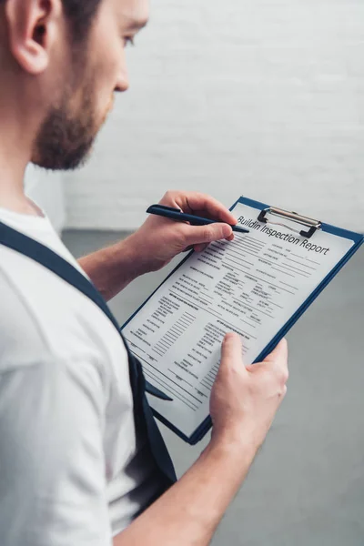 Cropped shoot of adult repairman making notes in clipboard in kitchen — Stock Photo