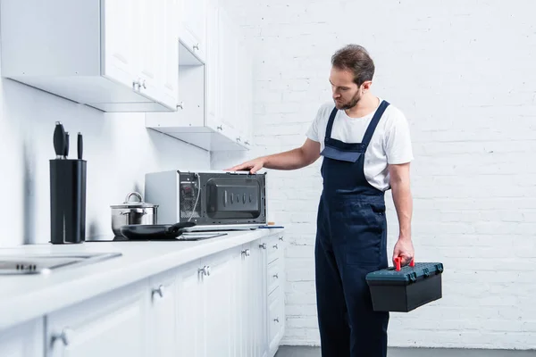 Дорослий майстер з інструментальною коробкою перевірка мікрохвильової печі на кухні — стокове фото