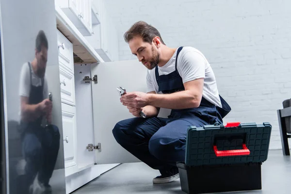 Heimwerker mit Zange kontrolliert Spüle in Küche — Stockfoto