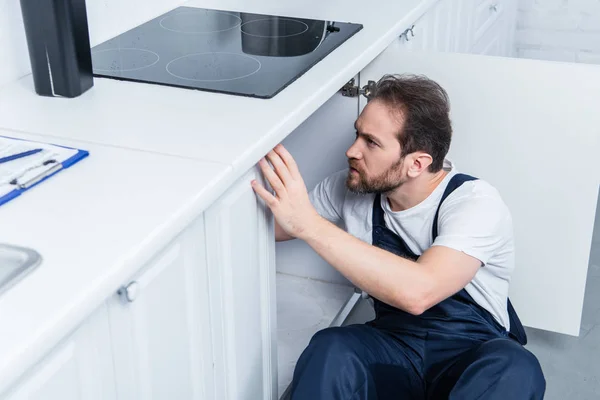 High angle view of handyman in working overall fixing oven in kitchen — Stock Photo
