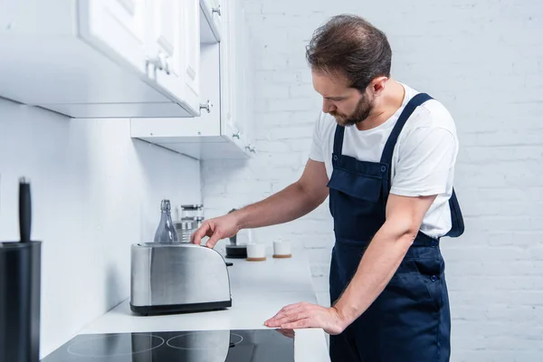 Craftsman in working overall fixing toaster in kitchen — Stock Photo