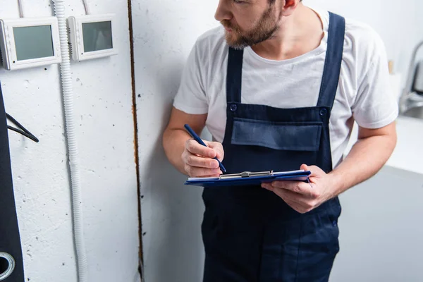 Cropped image of adult electrician with clipboard checking electrical panel — Stock Photo