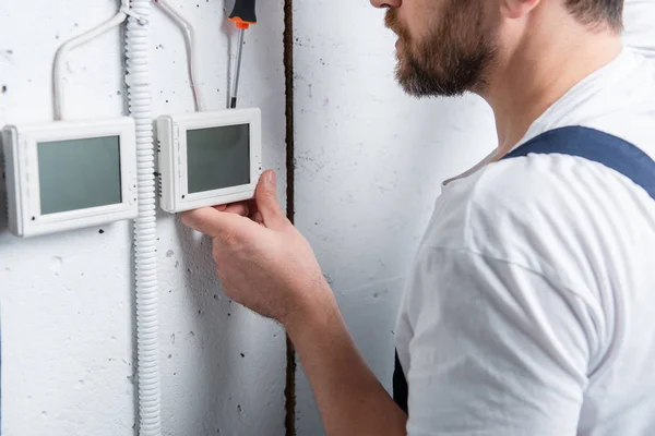 Disparo recortado de electricista masculino con sujetapapeles fijación caja eléctrica por destornillador - foto de stock