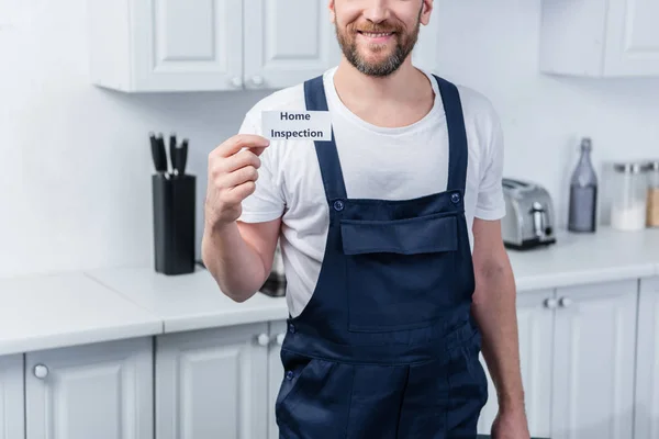 Cropped shot of male handyman holding toolbox and showing card with lettering home inspection — Stock Photo