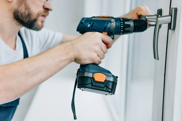 Partial view of handyman fixing window handle by electric drill — Stock Photo