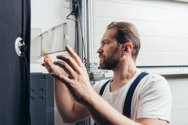 Hombre concentrado barbudo manitas comprobación de la caja eléctrica - foto de stock