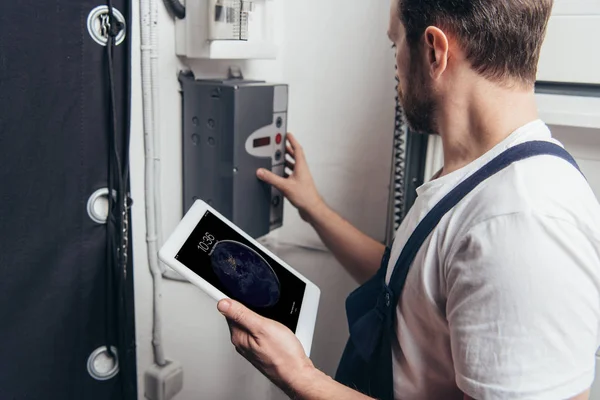 Eletricista masculino adulto usando tablet ipad e verificando caixa elétrica — Fotografia de Stock