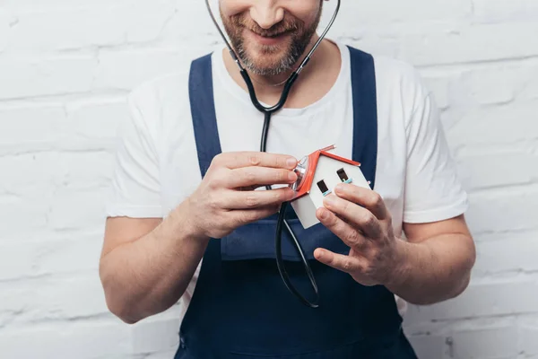 Partial view of male handyman checking house figure by stethoscope, home inspection concept — Stock Photo