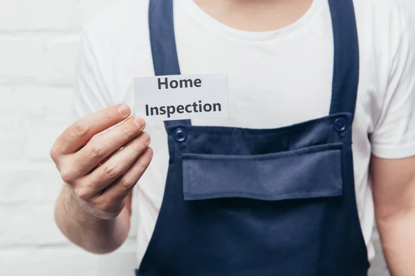 Cropped image of male craftsman showing card with lettering home inspection — Stock Photo