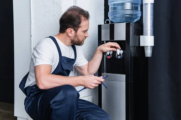 Reparador com prancheta verificando refrigerador de água quebrado — Fotografia de Stock