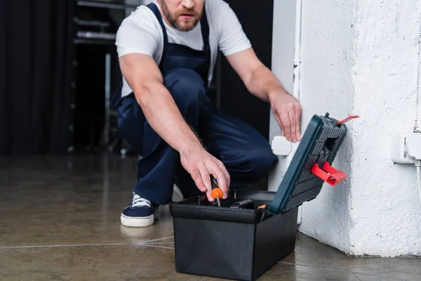 Image recadrée de l'électricien mâle prenant tournevis de la boîte à outils tout en réparant prise de courant — Photo de stock