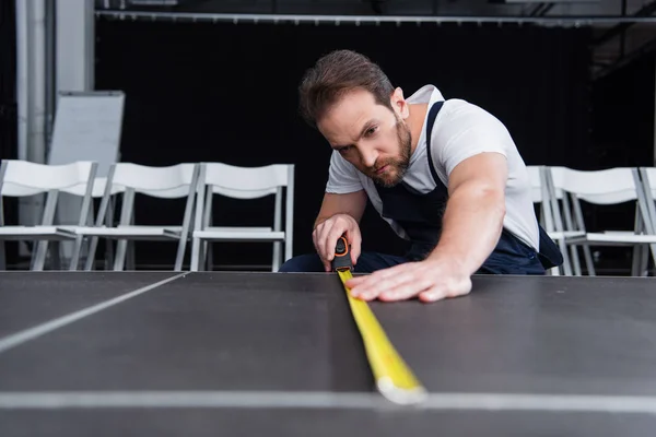 Концентрований чоловічий майстер в робочому загальному вимірюванні підлоги за допомогою вимірювальної стрічки — стокове фото
