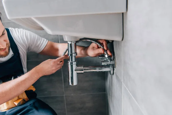 Partial view of male plumber in working overall fixing sink in bathroom — Stock Photo