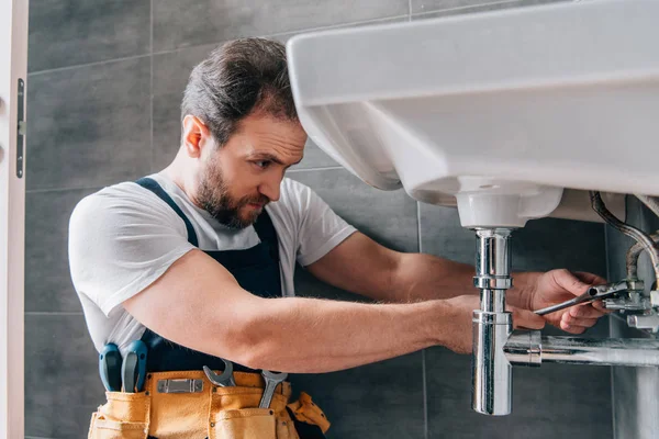 Encanador masculino focado em trabalhar pia de fixação global no banheiro — Fotografia de Stock