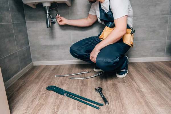 Plan recadré de plombier masculin avec ceinture d'outils de réparation évier dans la salle de bain — Photo de stock